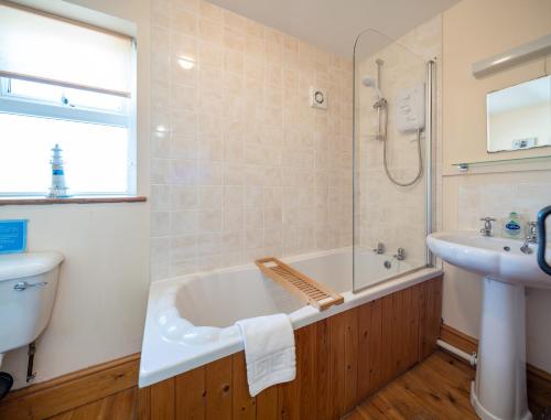 a bathroom with a bath tub and a sink at Wrth y Nant in Saint Ishmael