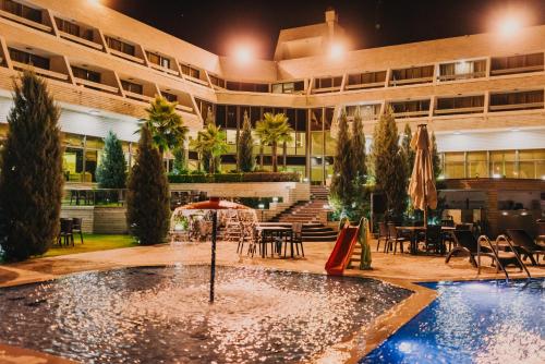 a hotel courtyard with a pool and tables and chairs at Ashur Hotel in Dokan