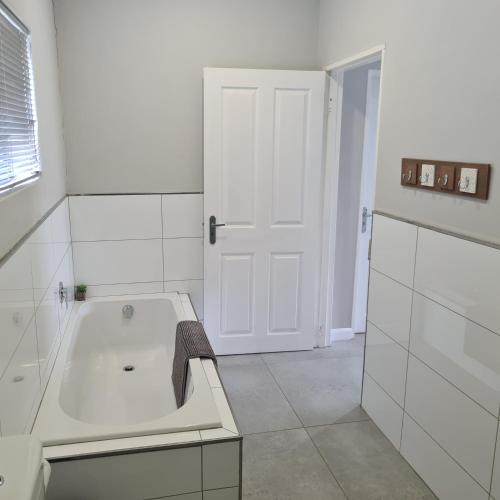 baño blanco con bañera y puerta blanca en Clarens Escape (Unit 2), en Clarens