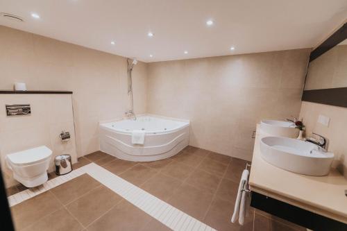 a bathroom with a tub and a toilet and a sink at Ashur Hotel in Dokan