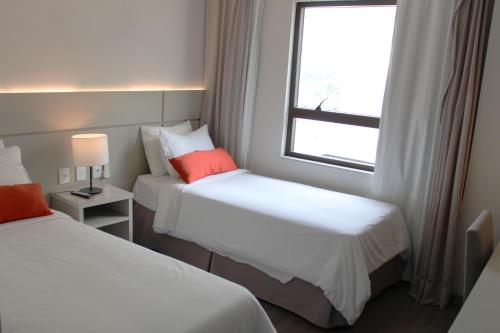 a hotel room with two beds and a window at Samba Tres Rios in Três Rios