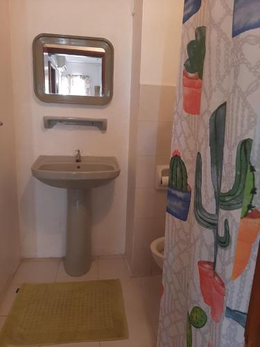 a bathroom with a sink and a shower curtain at Obelix Apartment in Grand Baie