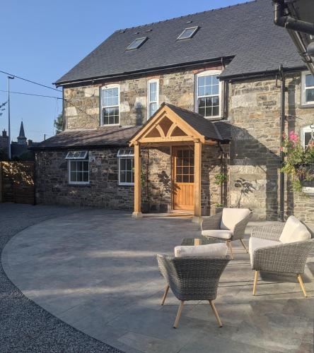 a stone house with chairs and a patio at Cambrian House B & B in Carno