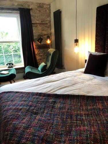 a bedroom with a bed with two chairs and a window at Cambrian House B & B in Carno