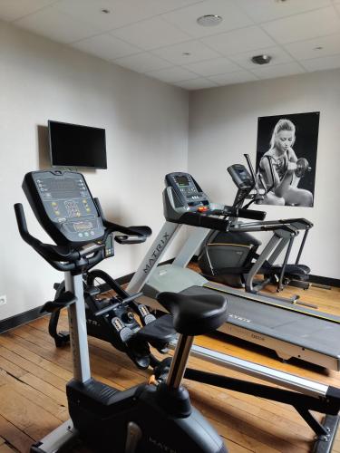 a gym with two exercise bikes and a treadmill at The Originals Boutique, Hôtel de l'Univers, Montluçon in Montluçon