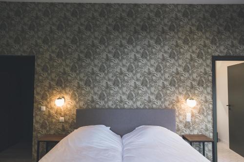 a bedroom with a bed with two pillows and a wall at So'House Manor in Spa