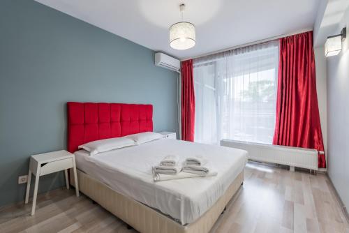 a bedroom with a large bed with red headboard and a window at Downtown Accommodation in Bucharest