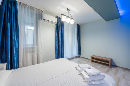 a bedroom with a large white bed with blue curtains at Downtown Accommodation in Bucharest