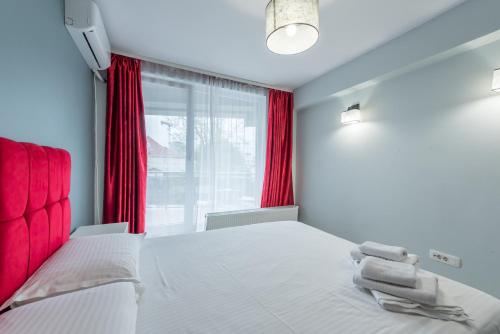 a bedroom with a large bed with red curtains at Downtown Accommodation in Bucharest