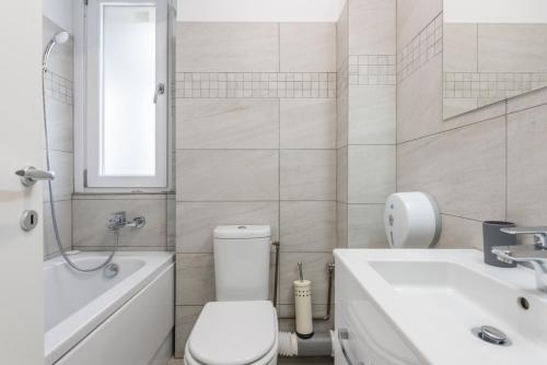a white bathroom with a toilet and a sink at Downtown Accommodation in Bucharest