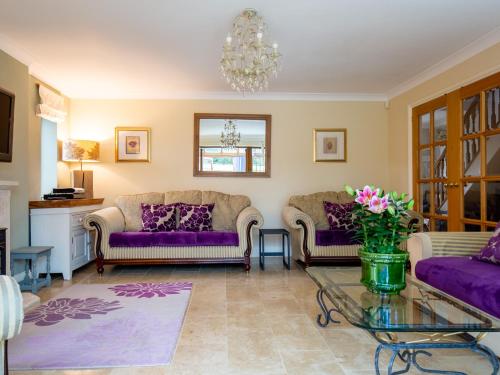 ein Wohnzimmer mit lila Sofas und einem Glastisch in der Unterkunft Kingfisher Cottage in Winchcombe