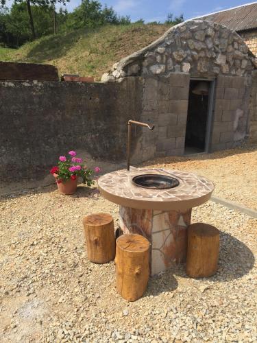 a stone table with a stone oven in a yard at Nyugalmas Vendégház in Lénárddaróc