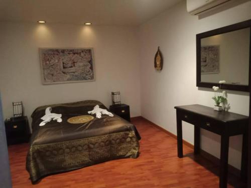 a bedroom with a bed and a table and a mirror at Sandy Home in Ban Thai Don (2)
