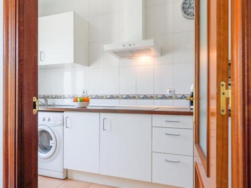 una cucina con mobili bianchi, lavatrice e asciugatrice di Alcalá del rio! bajo B ad Alcalá del Río