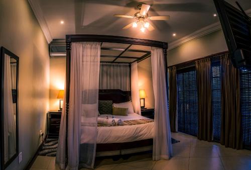 a bedroom with a canopy bed and a ceiling fan at Waterfalls Boutique Hotel in Pretoria