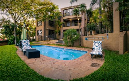 a swimming pool in front of a house at Waterfalls Boutique Hotel in Pretoria