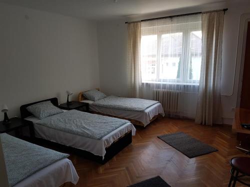 a room with three beds and a window at Kuckó Apartman Berente in Berente