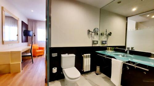 La salle de bains est pourvue de toilettes, d'un lavabo et d'un miroir. dans l'établissement Holiday Inn Madrid - Las Tablas, an IHG Hotel, à Madrid