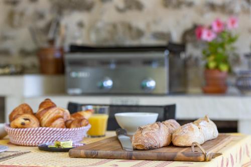a table with bread and croissants and a plate of pastries at Les Chambres du Lavoir Vert in Tourbes