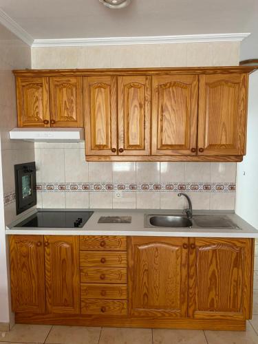 a kitchen with wooden cabinets and a sink at Berlin Lovely in Gran Tarajal