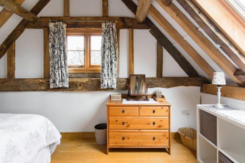 a bedroom with a bed and a dresser and a window at Old Barn Cottage in Horley
