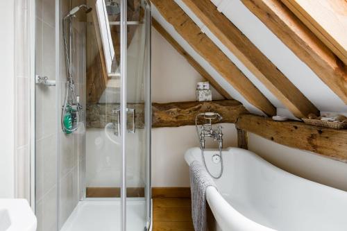 a bathroom with a shower and a bath tub at Old Barn Cottage in Horley