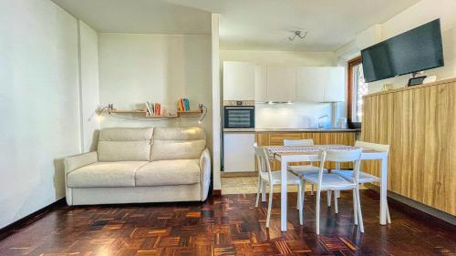 sala de estar con mesa, sofá y cocina en Appartamento Winter Garden - Affitti Brevi Italia, en Bardonecchia