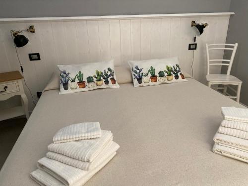a bed with four pillows and towels on it at Laserrafelice in Imperia
