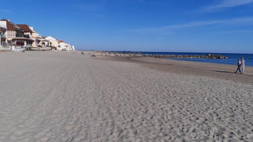 a person standing on a sandy beach next to the ocean at LE TRANSAT 40m de la plage in Palavas-les-Flots