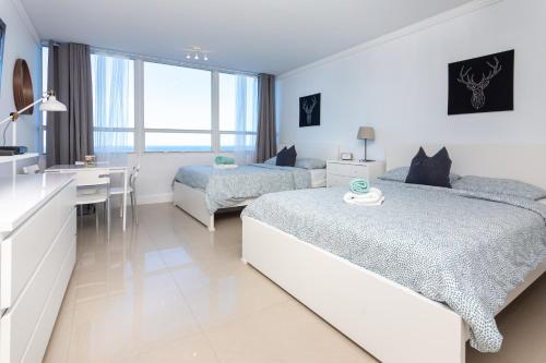a white bedroom with two beds and a desk at Girasole Rentals in Miami Beach