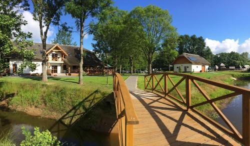 a wooden bridge over a river next to a house at Pensjonat Bajdarka in Suraż