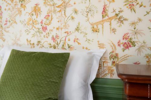 a bedroom with a green pillow and floral wallpaper at Hotel de Charme La Bonne Adresse - Logis hotels in Le Havre