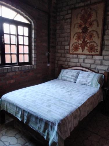 1 dormitorio con 1 cama en una pared de ladrillo en Chalé Rústico, en Palmeiras