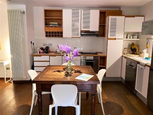 a kitchen with a wooden table with a vase of flowers on it at Casa Vacanza Fontanelle in Iseo