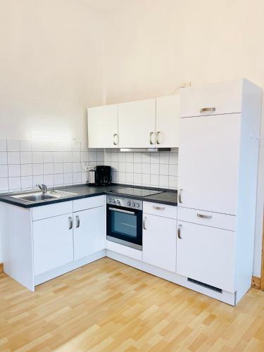 a kitchen with white cabinets and a stove top oven at Charmante Ferienwohnung mit Terrasse im Herzen von Norden in Norden