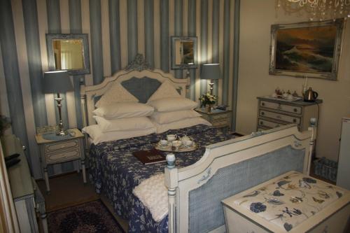 a bedroom with a bed and two night stands and two tables at A Summer Place Boutique Guest House in Bloemfontein