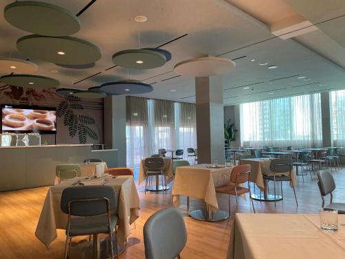a dining room with tables and chairs and a cafeteria at H2C Hotel Milanofiori in Assago
