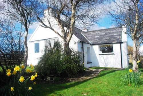 une maison blanche avec des fleurs dans la cour dans l'établissement Crepigill Cottage, à Portree