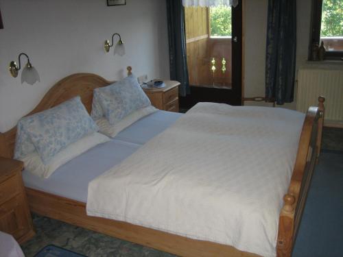 a bedroom with a bed with white sheets and blue pillows at Haus Obinger in Reit im Winkl
