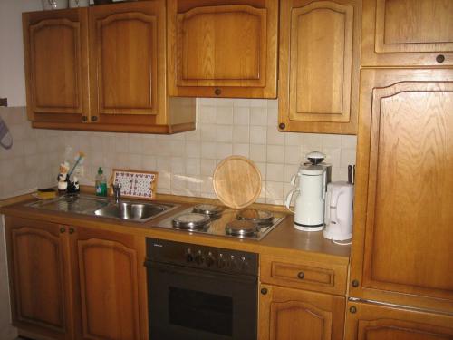 a kitchen with wooden cabinets and a sink and a stove at Haus Obinger in Reit im Winkl