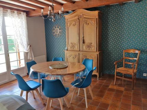 une salle à manger avec une table en bois et des chaises bleues dans l'établissement Maison calme avec jardin, Petit-Caux, à Bracquemont