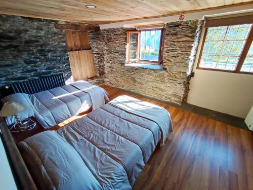 a bedroom with a bed and a stone wall at Mirador del Navia in Serandinas