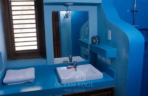 a blue bathroom with a sink and a mirror at Bella Vista in Las Terrenas