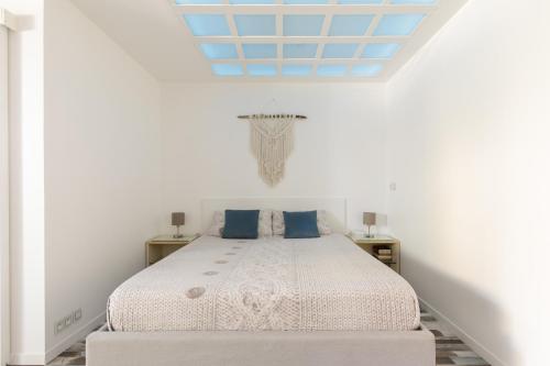 a white bedroom with a bed with blue pillows at Grand Studio neuf face port et plage, parking privé in Golfe-Juan