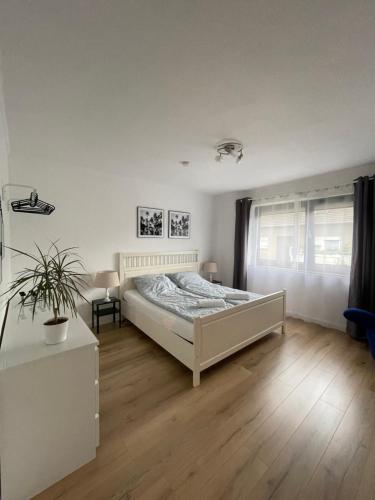 a white bedroom with a bed and a window at Moderne, helle Wohnung mit Terasse 15min bis OB Centro in Dinslaken
