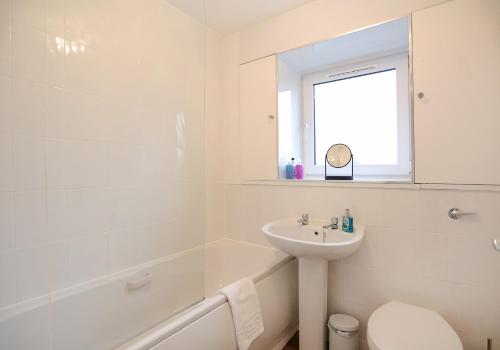 a white bathroom with a sink and a bath tub at The South Maybury Residence in Edinburgh