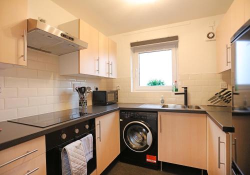 a kitchen with a washing machine and a sink at The South Maybury Residence in Edinburgh