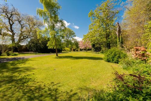 Drylaw House, Grade A Listed Mansion near City Centre في إدنبرة: حديقة بها أشجار وعشب وطريق