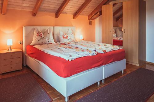 ein Schlafzimmer mit einem großen Bett mit einer roten Decke in der Unterkunft Armonia Altach in Altach