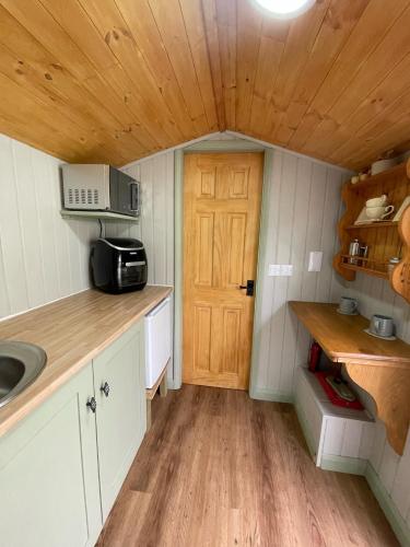 a small kitchen with a sink and a wooden door at Oakley View Shepherds Hut with hot tub in Whitby